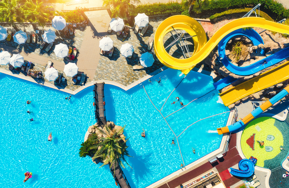 Aerial view of pool, aqua park, swimming people at sunset