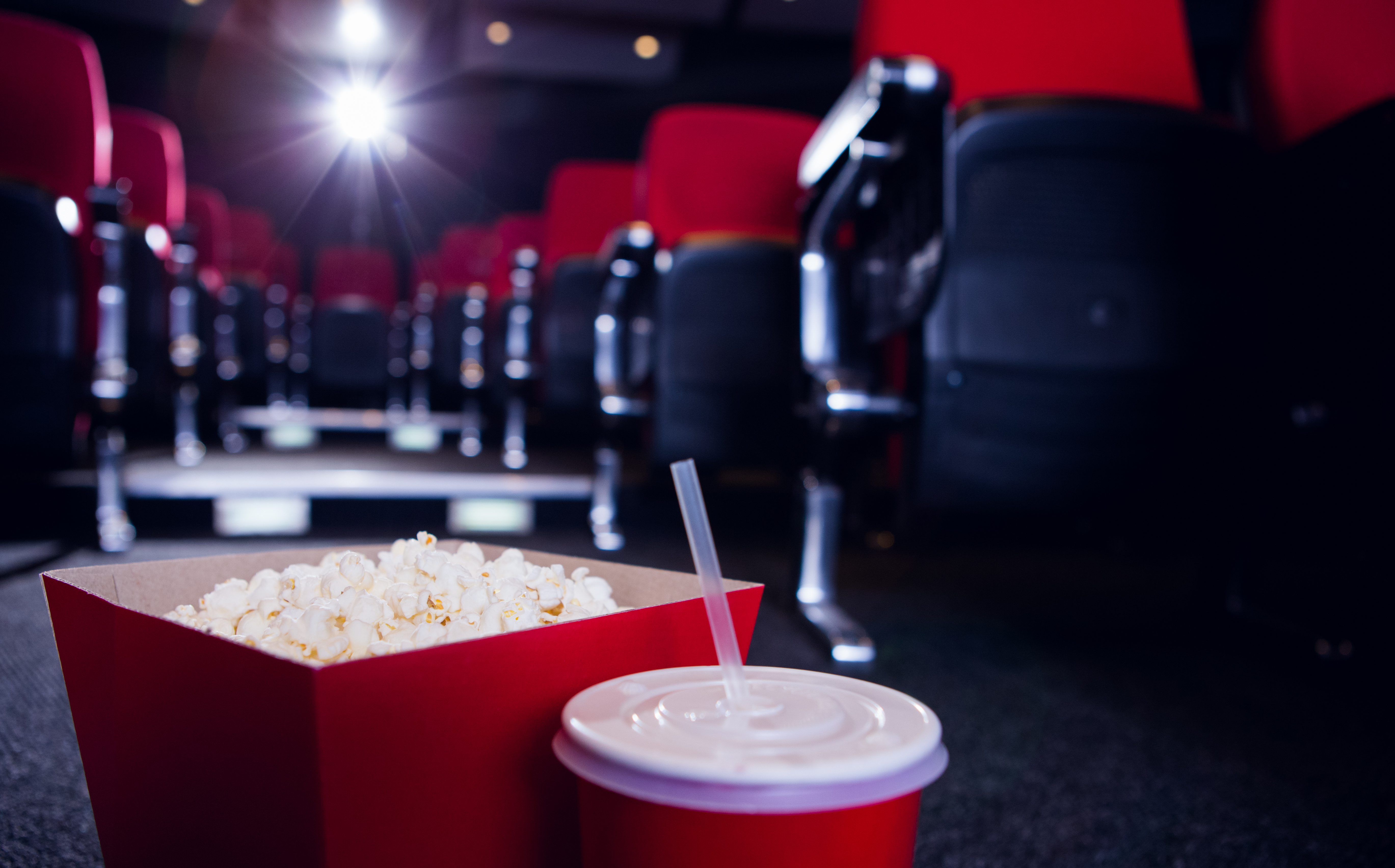 Empty rows of red seats with pop corn and drink on the floor at the cinema